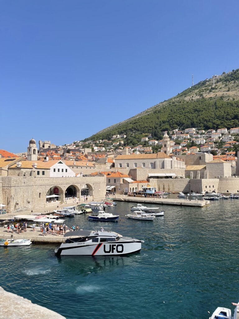 Boats, on the blue sea, surrounded by terracotta buildings in Dubrovnik's harbour